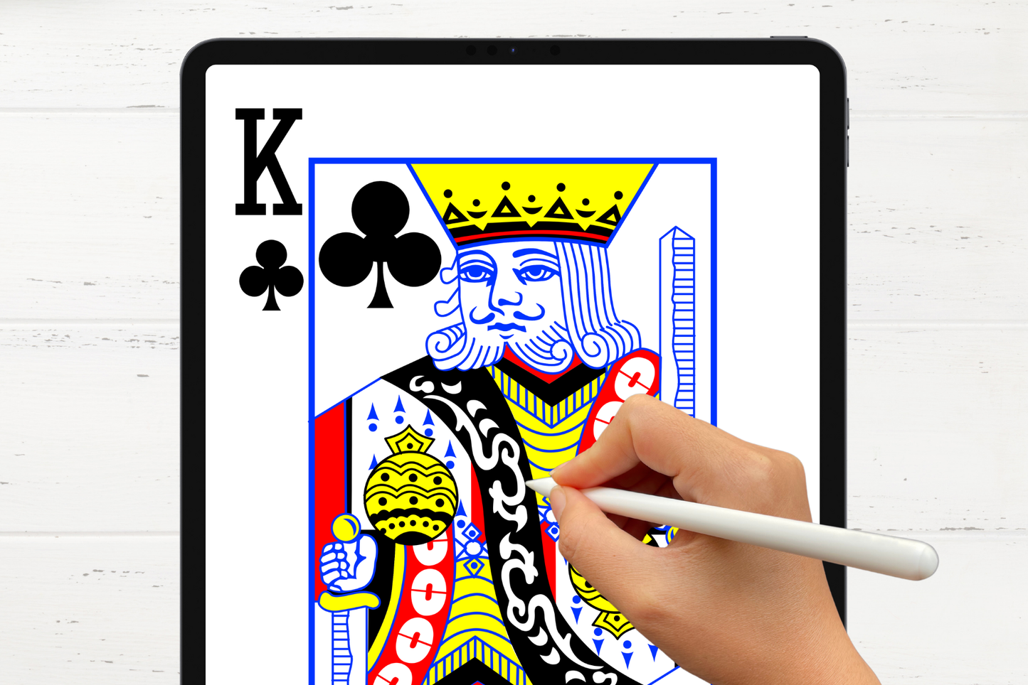 Hand using an Apple Pencil to color a digital King of Clubs playing card on an iPad.